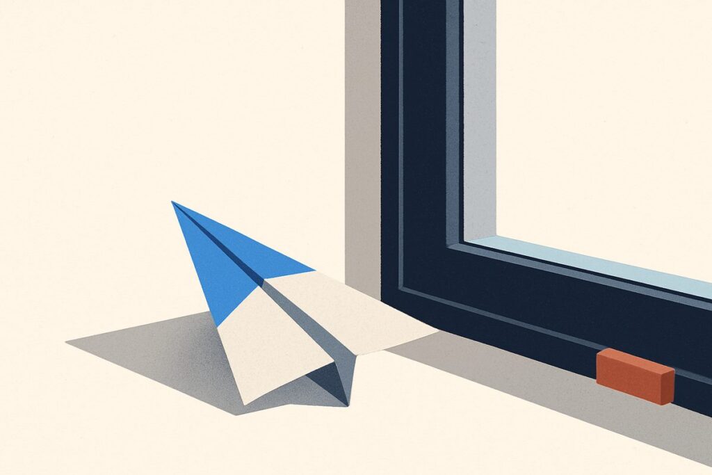A paper aeroplane resting on a windowsill beside a half-open window